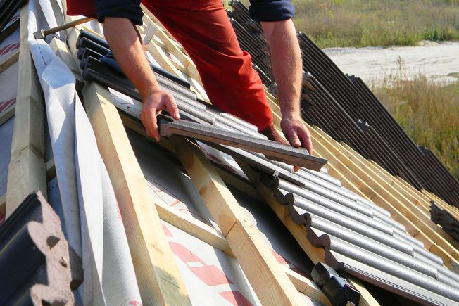 A roofer fitting roof tiles